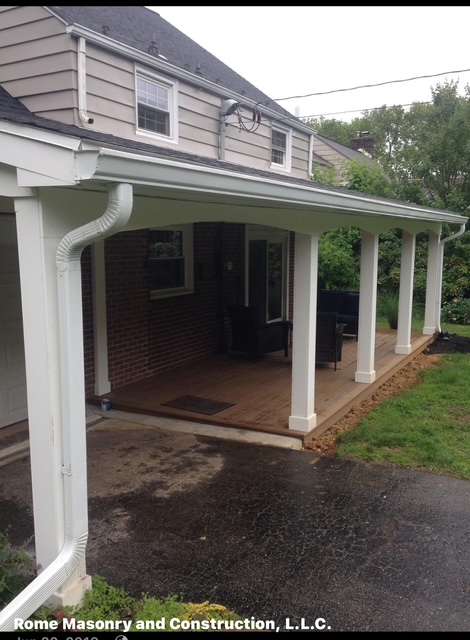 New covered porch with white columns over wood deck