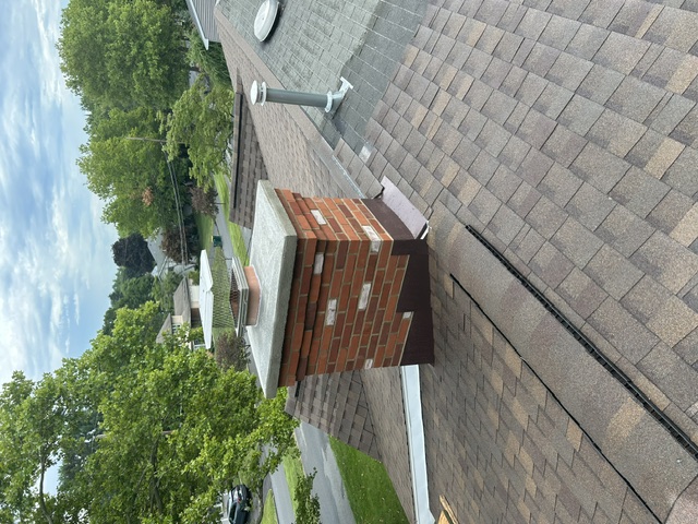 Rebuilt brick chimney with fresh flashing on shingle roof
