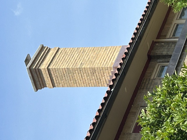 Tall corbeled brick chimney above tile roof line