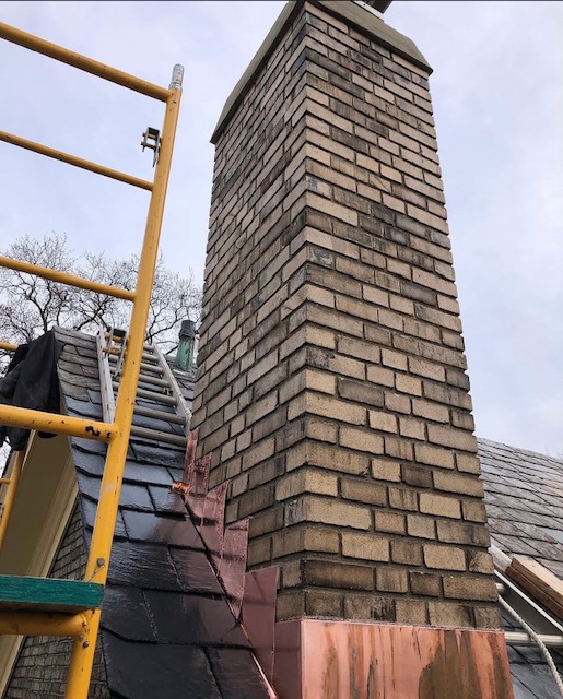 Brick chimney with new copper flashing viewed from slate roof in the Lehigh Valley, PA