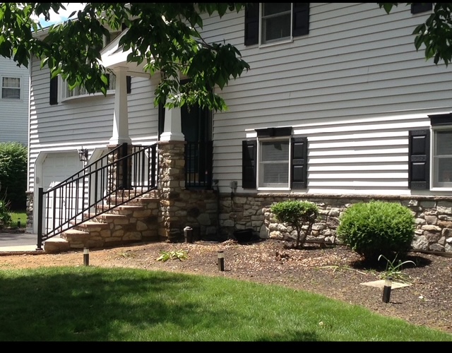 Natural stone veneer stoop and foundation with wrought iron railing