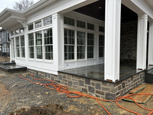 Natural stone veneer foundation on covered porch with bluestone floor