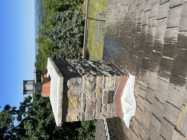 Stone chimney rebuild on hilltop home with valley view