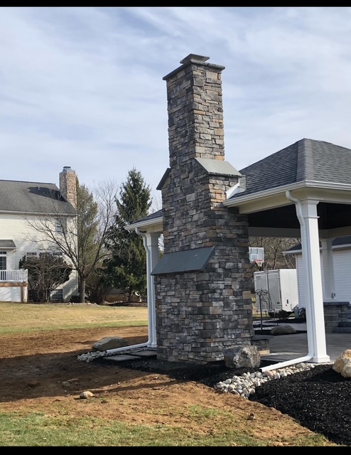 Freestanding stacked stone chimney beside covered pavilion