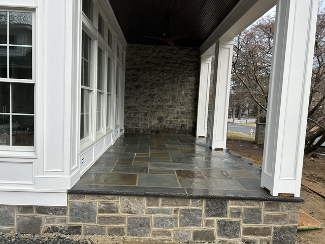 Covered porch with bluestone flooring and stacked stone wall